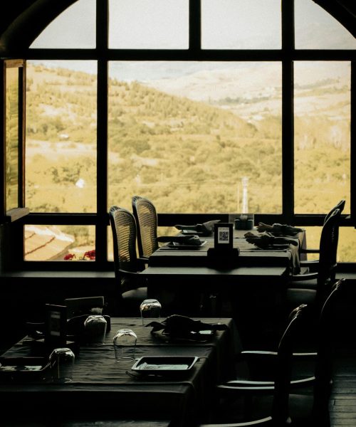 Elegant indoor dining with scenic mountain view through arched windows.